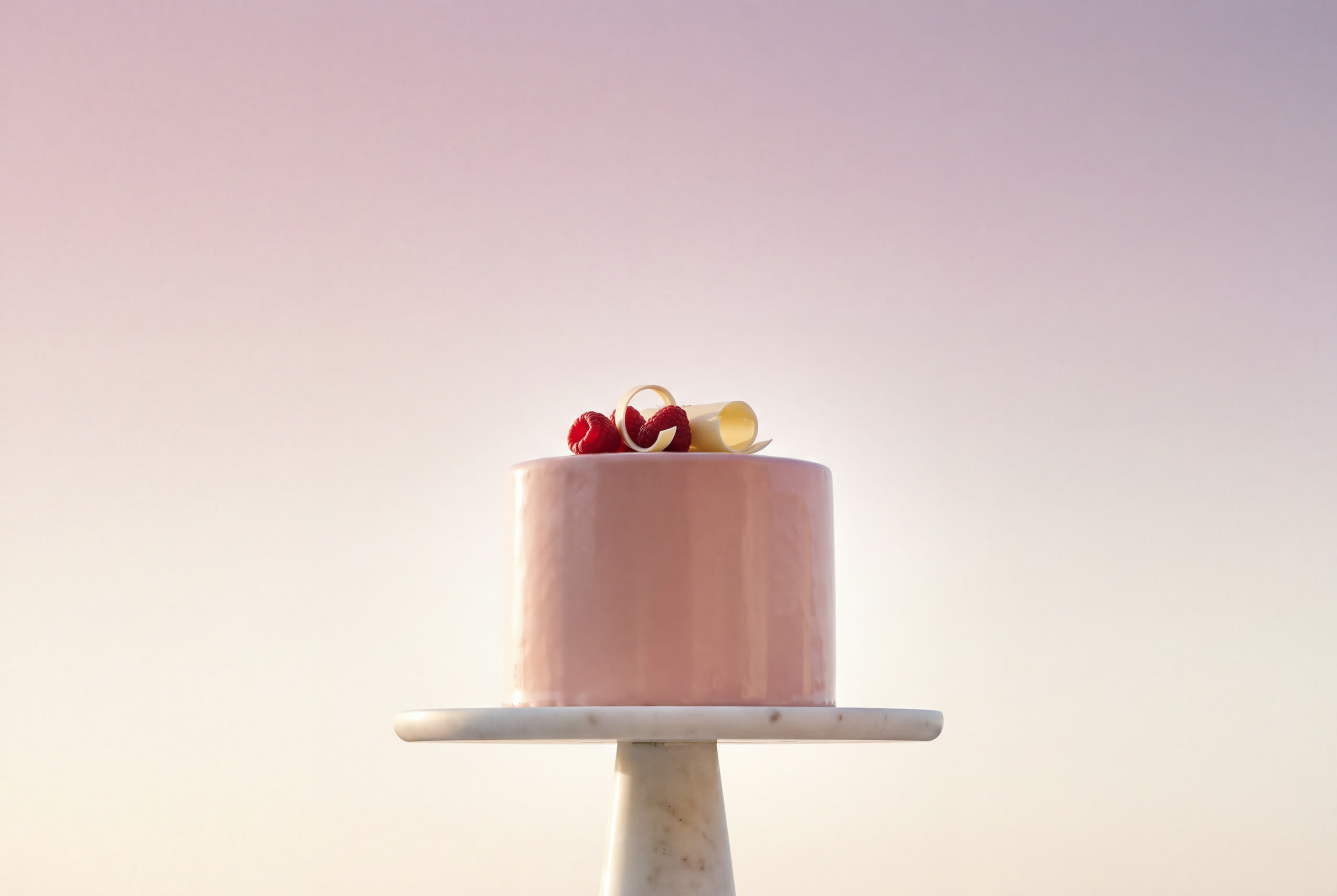A pink celebration cake on a marble pedestal