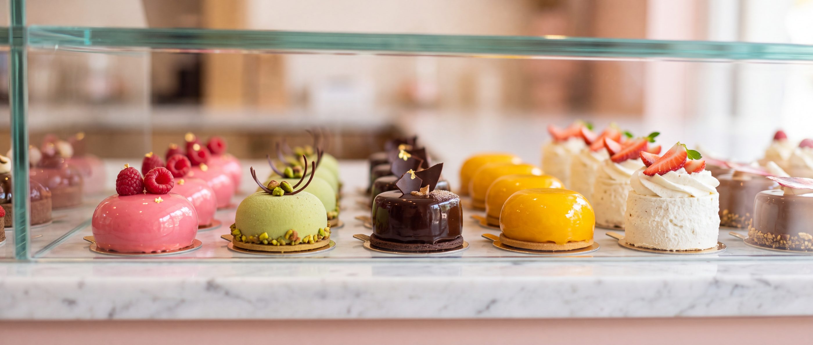 Rows of petit gâteaux in a glass cabinet