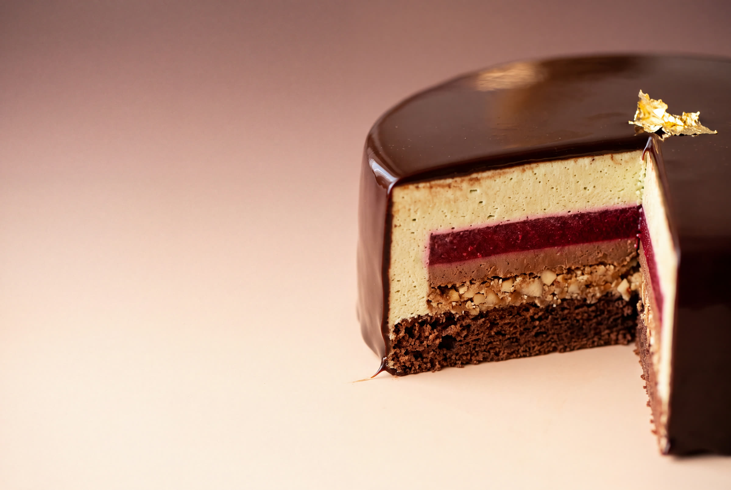 A slice cut from a chocolate entremet, showing its layers